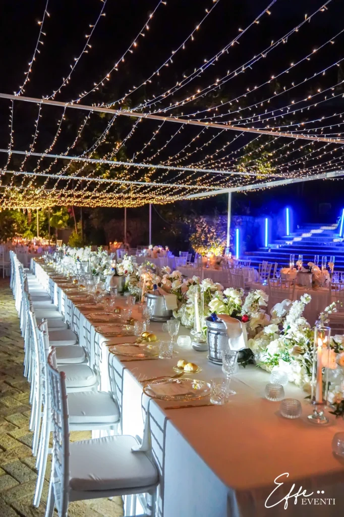 Mise en place total white su tavolo imperiale con milioni di luci scintillanti, perfetta per un matrimonio elegante.